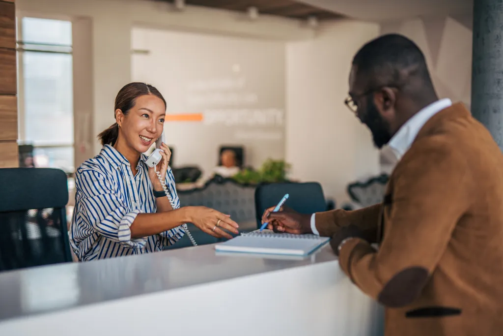 receptionist-assisting-client-and-talking-on-phone-0526-g-2238394361.jpg